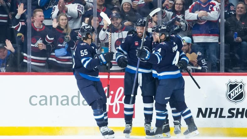 Jan 9, 2024; Winnipeg, Manitoba, CAN; Winnipeg Jets defenseman Brenden Dillon (5) is congratulated by his teammates on his goal against the Columbus Blue Jackets during the first period at Canada Life Centre. Mandatory Credit: Terrence Lee-USA TODAY Sports
