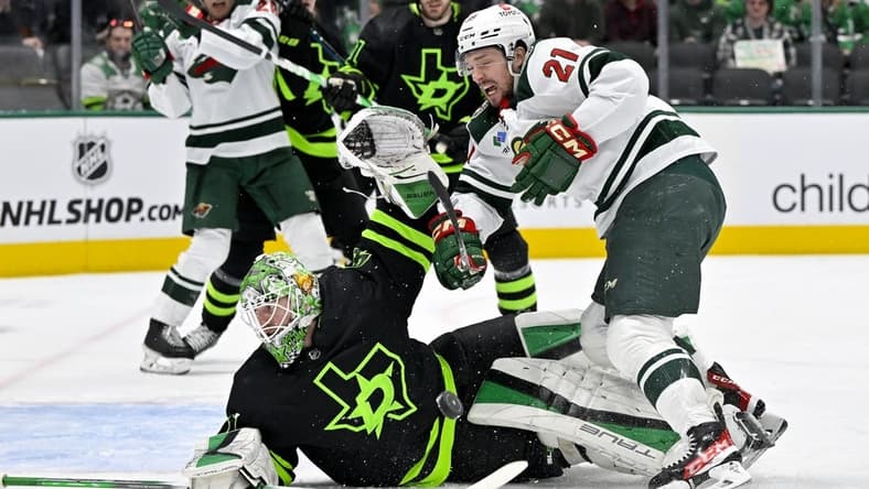 Jan 10, 2024; Dallas, Texas, USA; Minnesota Wild right wing Brandon Duhaime (21) is hit by a Wild slap shot as he attempts a shot on Dallas Stars goaltender Scott Wedgewood (41) during the first period at the American Airlines Center. Mandatory Credit: Jerome Miron-USA TODAY Sports