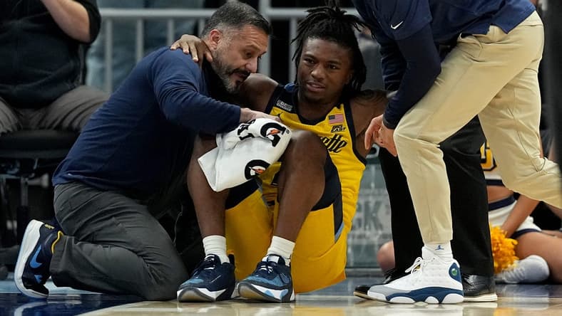 Marquette guard Sean Jones (22) is aided by a member of the training staff and head coach Shaka Smart, right, after being injured during the second half of their game Wednesday, January 10, 2024 at Fiserv Forum in Milwaukee, Wisconsin. Butler beat Marquette 69-62.