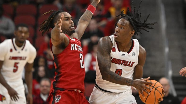 Jan 13, 2024; Louisville, Kentucky, USA; Louisville Cardinals guard Mike James (0) controls the ball against North Carolina State Wolfpack guard Kam Woods (2) during the first half at KFC Yum! Center. Mandatory Credit: Jamie Rhodes-USA TODAY Sports