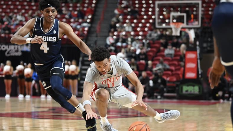 Jan 13, 2024; Las Vegas, Nevada, USA; UNLV Rebels guard Dedan Thomas Jr. (11) falls near Utah State Aggies guard Ian Martinez (4) during the first half at Thomas & Mack Center. Mandatory Credit: Candice Ward-USA TODAY Sports