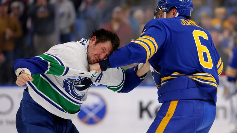 Jan 13, 2024; Buffalo, New York, USA;  Buffalo Sabres defenseman Erik Johnson (6) and Vancouver Canucks center J.T. Miller (9) fight during the second period at KeyBank Center. Mandatory Credit: Timothy T. Ludwig-USA TODAY Sports