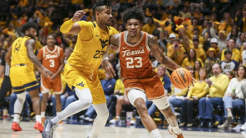 Jan 13, 2024; Morgantown, West Virginia, USA; Texas Longhorns forward Dillon Mitchell (23) drives baseline against West Virginia Mountaineers forward Josiah Harris (22) during the first half at WVU Coliseum. Mandatory Credit: Ben Queen-USA TODAY Sports