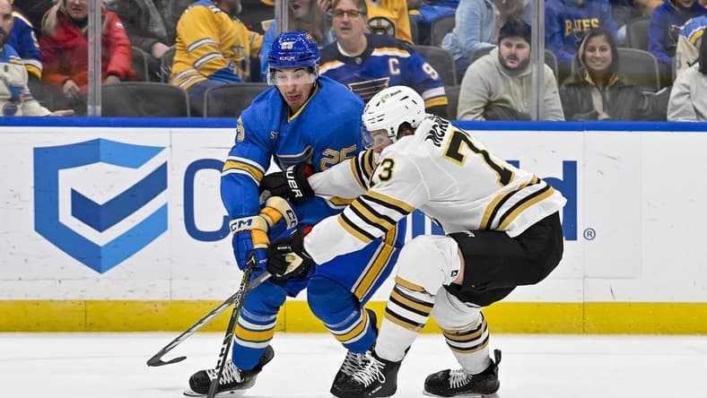 Jan 13, 2024; St. Louis, Missouri, USA;  St. Louis Blues center Jordan Kyrou (25) and Boston Bruins defenseman Charlie McAvoy (73) battle for the puck during the second period at Enterprise Center. Mandatory Credit: Jeff Curry-USA TODAY Sports