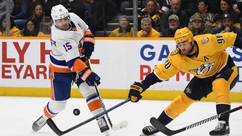Jan 13, 2024; Nashville, Tennessee, USA; New York Islanders right wing Cal Clutterbuck (15) shoots the puck against Nashville Predators center Ryan O'Reilly (90) during the second period at Bridgestone Arena. Mandatory Credit: Christopher Hanewinckel-USA TODAY Sports