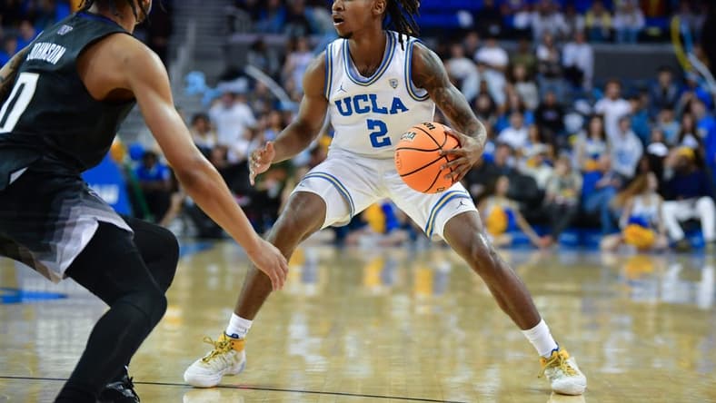 January 14, 2024; Los Angeles, California, USA; UCLA Bruins guard Dylan Andrews (2) controls the ball against Washington Huskies guard Koren Johnson (0) during the second half at Pauley Pavilion. Mandatory Credit: Gary A. Vasquez-USA TODAY Sports