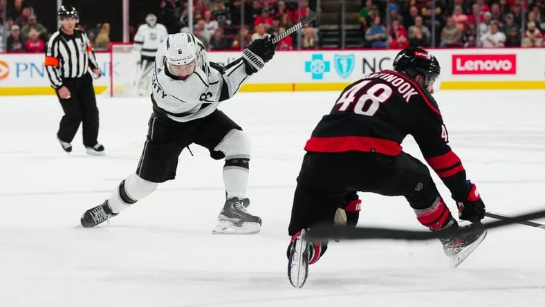 Jan 15, 2024; Raleigh, North Carolina, USA; Los Angeles Kings defenseman Drew Doughty (8) takes a shot past Carolina Hurricanes left wing Jordan Martinook (48) during the second period at PNC Arena. Mandatory Credit: James Guillory-USA TODAY Sports