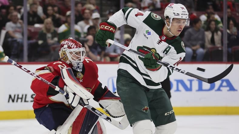 Jan 19, 2024; Sunrise, Florida, USA; Minnesota Wild center Joel Eriksson Ek (14) attempts to deflect the puck against Florida Panthers goaltender Sergei Bobrovsky (72) during the first period at Amerant Bank Arena. Mandatory Credit: Sam Navarro-USA TODAY Sports