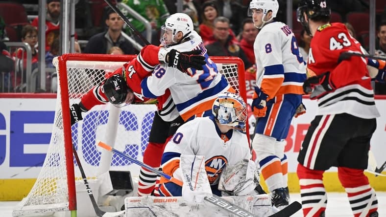 Jan 19, 2024; Chicago, Illinois, USA; New York Islanders defenseman Alexander Romanov (28) collides with Chicago Blackhawks forward Jason Dickinson (16) behind goaltender Ilya Sorokin (30) in the first period at United Center. Mandatory Credit: Jamie Sabau-USA TODAY Sports