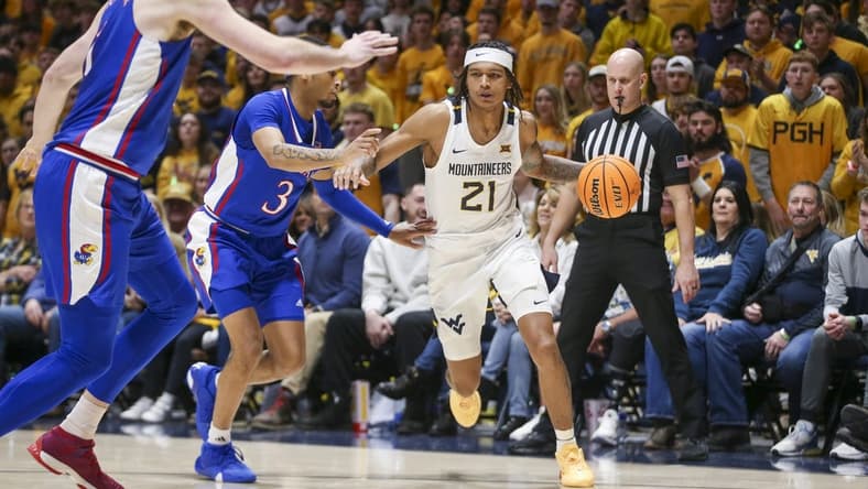 Jan 20, 2024; Morgantown, West Virginia, USA; West Virginia Mountaineers guard RaeQuan Battle (21) dribbles the ball past Kansas Jayhawks guard Dajuan Harris Jr. (3) during the second half at WVU Coliseum. Mandatory Credit: Ben Queen-USA TODAY Sports
