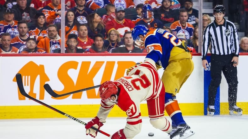 Jan 20, 2024; Calgary, Alberta, CAN; Calgary Flames right wing Matt Coronato (27) and Edmonton Oilers center Leon Draisaitl (29) battles for the puck during the second period at Scotiabank Saddledome. Mandatory Credit: Sergei Belski-USA TODAY Sports