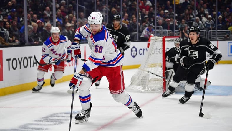 Jan 20, 2024; Los Angeles, California, USA; New York Rangers left wing Will Cuylle (50) moves the puck ahead of Los Angeles Kings defenseman Jordan Spence (21) durng the first period at Crypto.com Arena. Mandatory Credit: Gary A. Vasquez-USA TODAY Sports