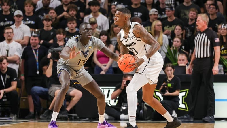 Jan 23, 2024; Orlando, Florida, USA; UCF Knights forward C.J. Walker (21) looks to pass against West Virginia Mountaineers forward Akok Akok (13) during the first half at Addition Financial Arena. Mandatory Credit: Mike Watters-USA TODAY Sports