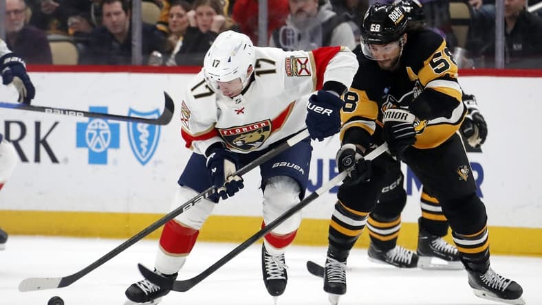 Jan 26, 2024; Pittsburgh, Pennsylvania, USA; Florida Panthers center Evan Rodrigues (17) moves the puck against pressure from Pittsburgh Penguins defenseman Kris Letang (58) during the second period at PPG Paints Arena. Mandatory Credit: Charles LeClaire-USA TODAY Sports