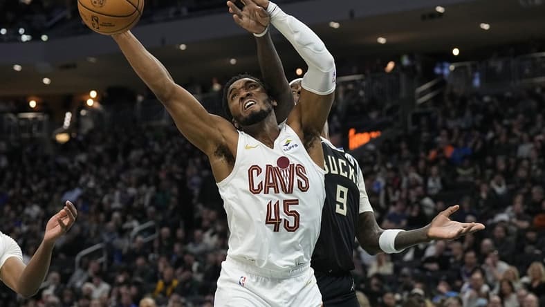 Jan 26, 2024; Milwaukee, Wisconsin, USA; Cleveland Cavaliers guard Donovan Mitchell (45) reaches for a rebound in front of Milwaukee Bucks forward Bobby Portis (9) during the second quarter at Fiserv Forum. Mandatory Credit: Jeff Hanisch-USA TODAY Sports