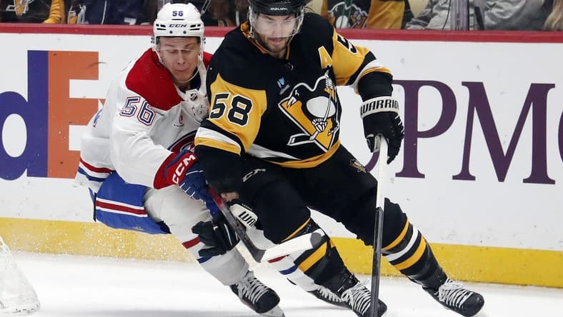 Jan 27, 2024; Pittsburgh, Pennsylvania, USA; Pittsburgh Penguins defenseman Kris Letang (58) moves the puck ahead of Montreal Canadiens right wing Jesse Ylonen (56) during the second period at PPG Paints Arena. Mandatory Credit: Charles LeClaire-USA TODAY Sports