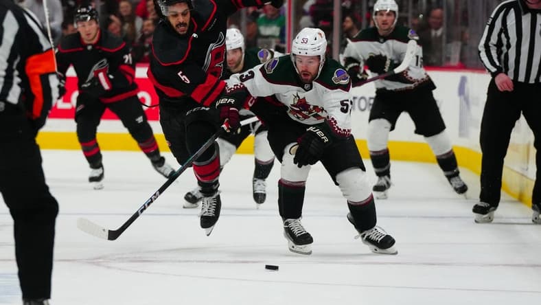 Jan 27, 2024; Raleigh, North Carolina, USA; Arizona Coyotes left wing Michael Carcone (53) and Carolina Hurricanes defenseman Jalen Chatfield (5) battle over the puck during the second period at PNC Arena. Mandatory Credit: James Guillory-USA TODAY Sports