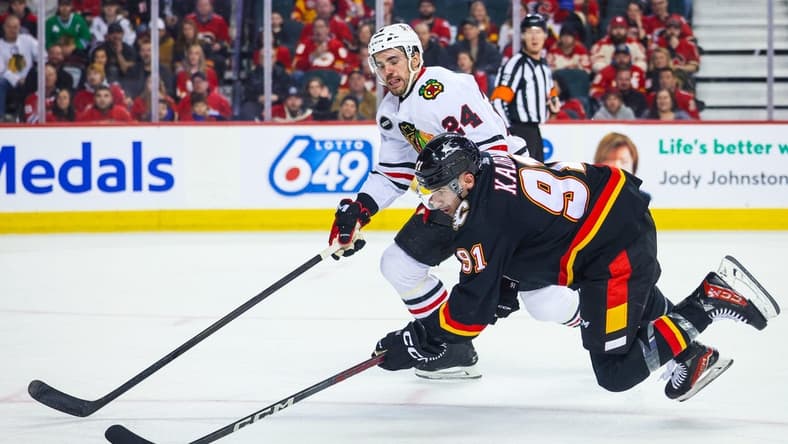 Jan 27, 2024; Calgary, Alberta, CAN; Calgary Flames center Nazem Kadri (91) controls the puck against Chicago Blackhawks defenseman Jaycob Megna (24) during the second period at Scotiabank Saddledome. Mandatory Credit: Sergei Belski-USA TODAY Sports