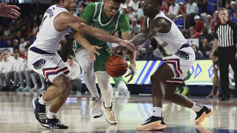 Jan 28, 2024; Boca Raton, Florida, USA; North Texas Mean Green guard CJ Noland (22) drives to the basket against Florida Atlantic Owls guard Bryan Greenlee (4) and guard Johnell Davis (1) during the first half at Eleanor R. Baldwin Arena. Mandatory Credit: Sam Navarro-USA TODAY Sports