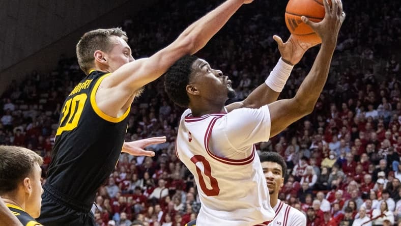 Jan 30, 2024; Bloomington, Indiana, USA; Indiana Hoosiers guard Xavier Johnson (0) shoots the ball while Iowa Hawkeyes forward Payton Sandfort (20) defends in the first half at Simon Skjodt Assembly Hall. Mandatory Credit: Trevor Ruszkowski-USA TODAY Sports