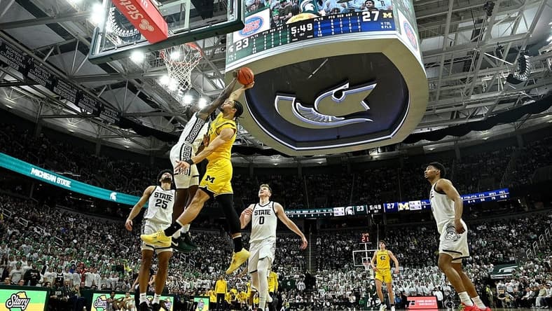 Jan 30, 2024; East Lansing, Michigan, USA; Michigan Wolverines forward Olivier Nkamhoua (13) gets blocked by Michigan State Spartans forward Coen Carr (55) during the first half at Jack Breslin Student Events Center. Mandatory Credit: Dale Young-USA TODAY Sports