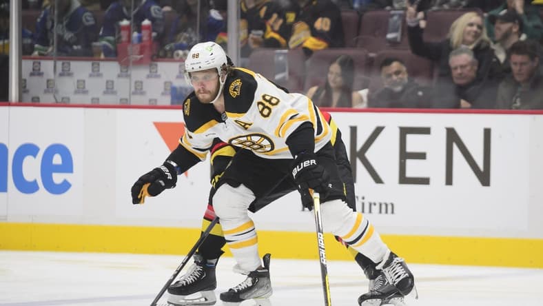 Feb 25, 2023; Vancouver, British Columbia, CAN;  Boston Bruins forward David Pastrnak  (88) reaches for the puck against the Vancouver Canucks during the first period at Rogers Arena. Mandatory Credit: Anne-Marie Sorvin-USA TODAY Sports