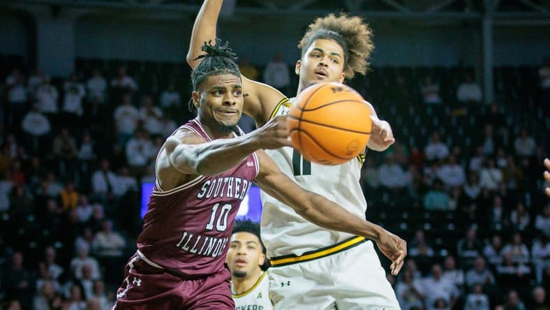 Dec 16, 2023; Wichita, Kansas, USA; Southern Illinois Salukis Xavier Johnson (10) passes around Wichita State Shockers forward Kenny Pohto (11) during the second half at Charles Koch Arena. Mandatory Credit: William Purnell-USA TODAY Sports