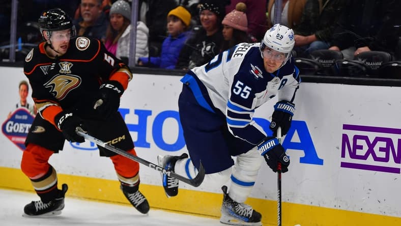 Jan 5, 2024; Anaheim, California, USA; Winnipeg Jets center Mark Scheifele (55) moves the puck ahead of Anaheim Ducks defenseman Urho Vaakanainen (5) during the first period at Honda Center. Mandatory Credit: Gary A. Vasquez-USA TODAY Sports