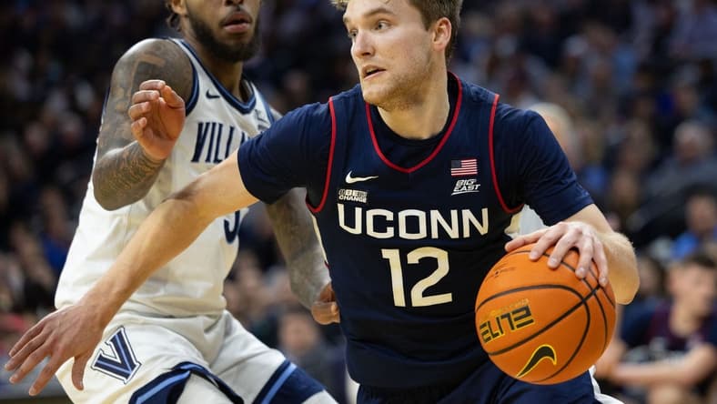 Jan 20, 2024; Philadelphia, Pennsylvania, USA; Connecticut Huskies guard Cam Spencer (12) drives past Villanova Wildcats guard Justin Moore (5) during the second half at Wells Fargo Center. Mandatory Credit: Bill Streicher-USA TODAY Sports