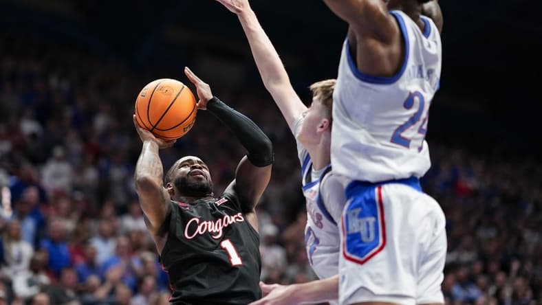 Feb 3, 2024; Lawrence, Kansas, USA; Houston Cougars guard Jamal Shead (1) shoots against Kansas Jayhawks guard Johnny Furphy (10) and forward K.J. Adams Jr. (24) during the first half at Allen Fieldhouse. Mandatory Credit: Jay Biggerstaff-USA TODAY Sports