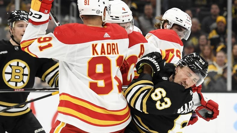 Feb 6, 2024; Boston, Massachusetts, USA; Boston Bruins left wing Brad Marchand (63) reacts after getting a cross check in the face by Calgary Flames center Martin Pospisil (76) during the first period at TD Garden. Mandatory Credit: Bob DeChiara-USA TODAY Sports