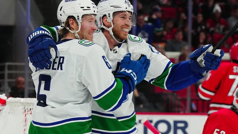 Feb 6, 2024; Raleigh, North Carolina, USA; Vancouver Canucks center Elias Lindholm (23) is congratulated by right wing Brock Boeser (6) after his goal against the Carolina Hurricanes during the second period at PNC Arena. Mandatory Credit: James Guillory-USA TODAY Sports