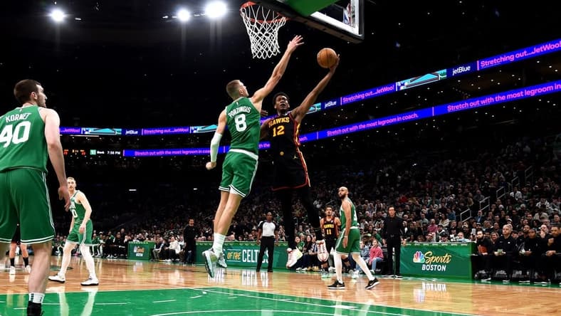 Feb 7, 2024; Boston, Massachusetts, USA;  Atlanta Hawks forward De'Andre Hunter (12) drives to the basket and gets fouled by Boston Celtics center Kristaps Porzingis (8) during the first half at TD Garden. Mandatory Credit: Bob DeChiara-USA TODAY Sports