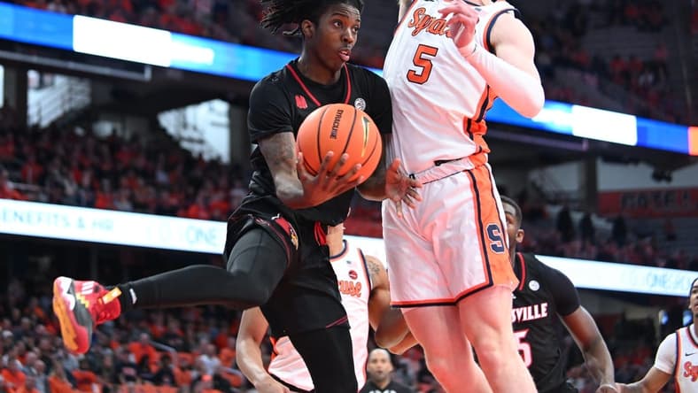 Feb 7, 2024; Syracuse, New York, USA; Louisville Cardinals guard Ty-Laur Johnson (4) passes the ball under the basket with Syracuse Orange guard Justin Taylor (5) defending in the first half at the JMA Wireless Dome. Mandatory Credit: Mark Konezny-USA TODAY Sports