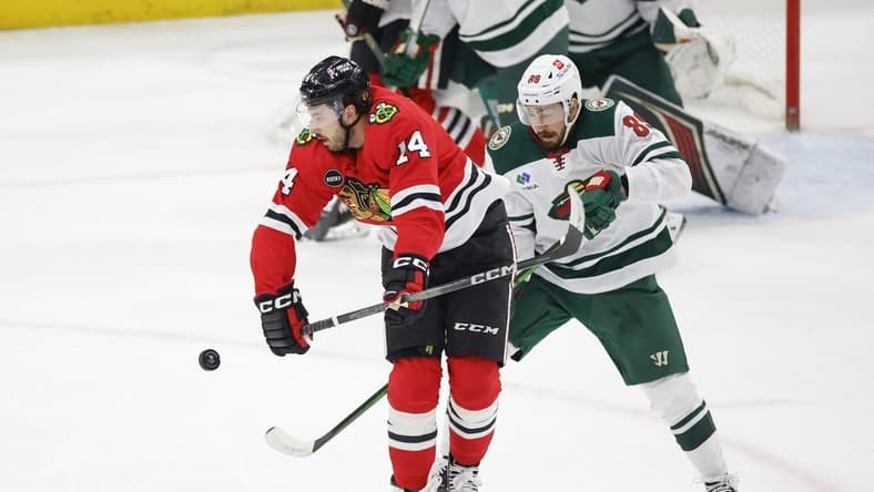 Feb 7, 2024; Chicago, Illinois, USA; Chicago Blackhawks left wing Boris Katchouk (14) battles for the puck with Minnesota Wild center Frederick Gaudreau (89) during the first period at United Center. Mandatory Credit: Kamil Krzaczynski-USA TODAY Sports