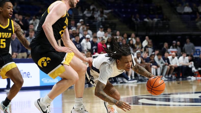 Feb 8, 2024; University Park, Pennsylvania, USA; Penn State Nittany Lions guard Ace Baldwin Jr (1) looses his footing while dribbling the ball around Iowa Hawkeyes forward Ben Krikke (23) during the first half at Bryce Jordan Center. Mandatory Credit: Matthew O'Haren-USA TODAY Sports