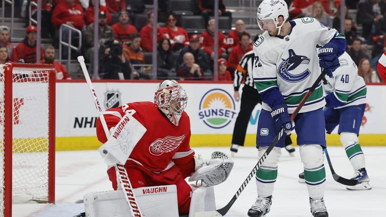 Feb 10, 2024; Detroit, Michigan, USA; Detroit Red Wings goaltender Alex Lyon (34) makes a save in front of Vancouver Canucks center Elias Lindholm (23) in the first period at Little Caesars Arena. Mandatory Credit: Rick Osentoski-USA TODAY Sports