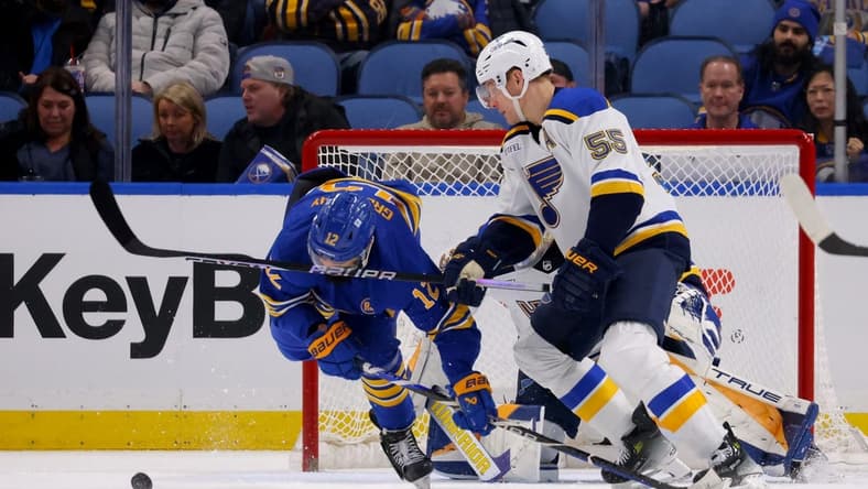 Feb 10, 2024; Buffalo, New York, USA; Buffalo Sabres left wing Jordan Greenway (12) gets a stick in the face by St. Louis Blues defenseman Colton Parayko (55) as they go after a loose puck during the third period at KeyBank Center. Mandatory Credit: Timothy T. Ludwig-USA TODAY Sports