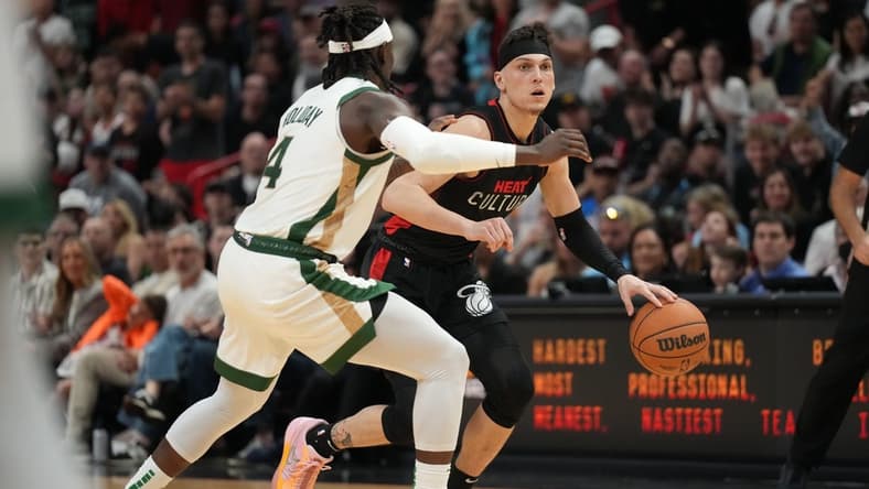 Feb 11, 2024; Miami, Florida, USA; Miami Heat guard Tyler Herro (14) dribbles the ball against Boston Celtics guard Jrue Holiday (4) defends during the second half at Kaseya Center. Mandatory Credit: Jim Rassol-USA TODAY Sports