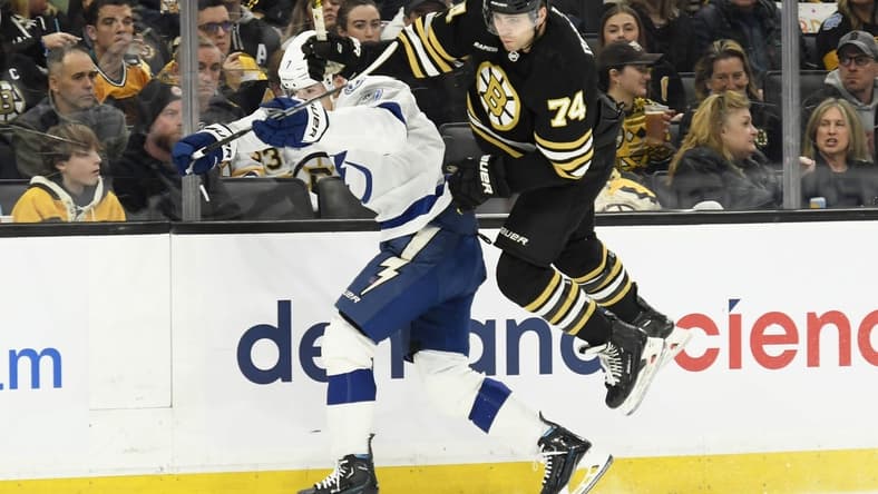 Feb 13, 2024; Boston, Massachusetts, USA; Boston Bruins left wing Jake DeBrusk (74) leaps by Tampa Bay Lightning defenseman Haydn Fleury (7) during the first period at TD Garden. Mandatory Credit: Bob DeChiara-USA TODAY Sports