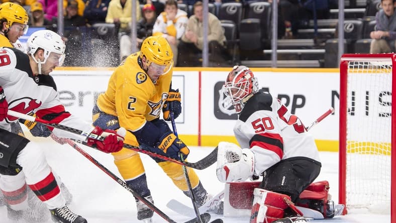 Feb 13, 2024; Nashville, Tennessee, USA; New Jersey Devils goaltender Nico Daws (50) blocks the shot of Nashville Predators defenseman Luke Schenn (2) during the first period at Bridgestone Arena. Mandatory Credit: Steve Roberts-USA TODAY Sports
