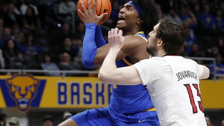 Feb 17, 2024; Pittsburgh, Pennsylvania, USA; Pittsburgh Panthers forward Blake Hinson (left) goes to the basket against Louisville Cardinals forward Danilo Jovanovich (13) during the first half at the Petersen Events Center. Mandatory Credit: Charles LeClaire-USA TODAY Sports