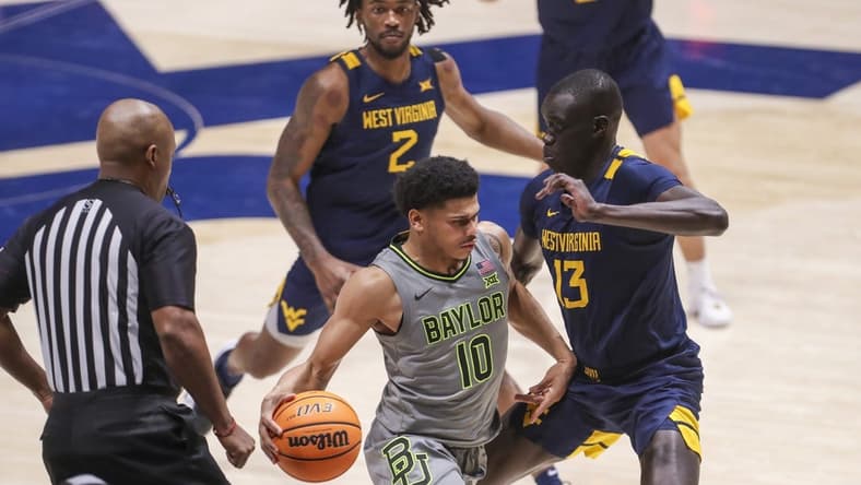 Feb 17, 2024; Morgantown, West Virginia, USA; Baylor Bears guard RayJ Dennis (10) dribbles against West Virginia Mountaineers forward Akok Akok (13) during the second half at WVU Coliseum. Mandatory Credit: Ben Queen-USA TODAY Sports