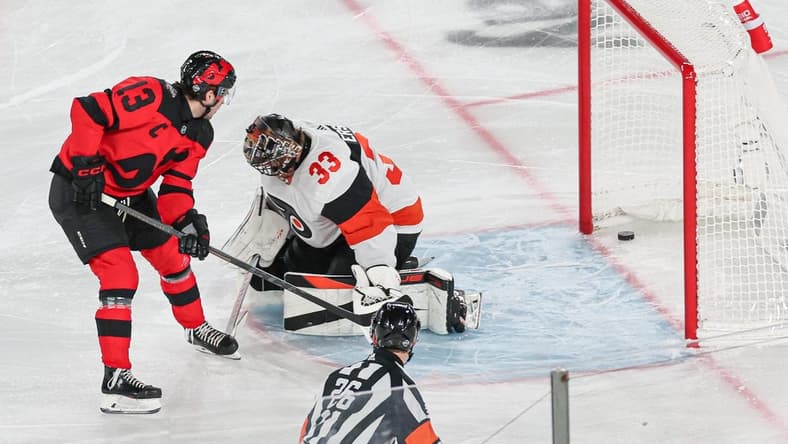 Feb 17, 2024; East Rutherford, New Jersey, USA; New Jersey Devils center Nico Hischier (13) scores a goal past Philadelphia Flyers goaltender Samuel Ersson (33) during the first period in a Stadium Series ice hockey game at MetLife Stadium. Mandatory Credit: Vincent Carchietta-USA TODAY Sports