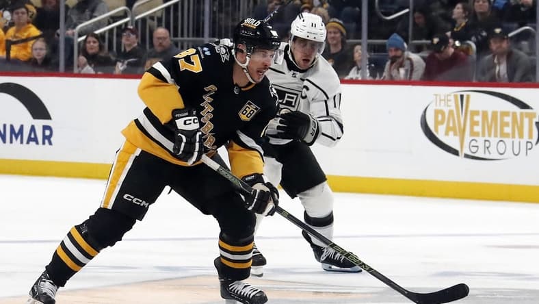 Feb 18, 2024; Pittsburgh, Pennsylvania, USA; Pittsburgh Penguins center Sidney Crosby (87) skates with the puck ahead of Los Angeles Kings center Anze Kopitar (11) during the third period at PPG Paints Arena. Los Angeles won 2-1. Mandatory Credit: Charles LeClaire-USA TODAY Sports