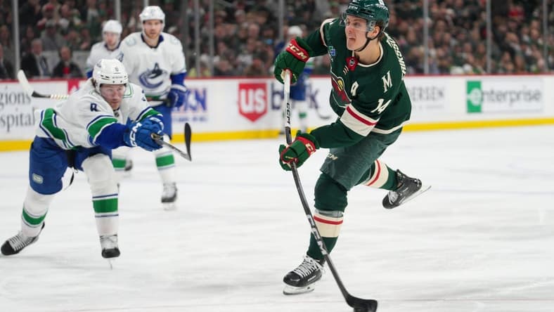Feb 19, 2024; Saint Paul, Minnesota, USA; Minnesota Wild center Joel Eriksson Ek (14) shoots as Vancouver Canucks right wing Conor Garland (8) defends in the second period at Xcel Energy Center. Mandatory Credit: Matt Blewett-USA TODAY Sports