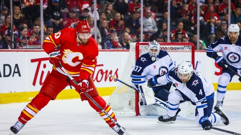Feb 19, 2024; Calgary, Alberta, CAN; Calgary Flames center Jonathan Huberdeau (10) passes the puck against the Winnipeg Jets during the second period at Scotiabank Saddledome. Mandatory Credit: Sergei Belski-USA TODAY Sports