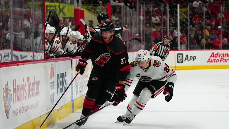 Feb 19, 2024; Raleigh, North Carolina, USA;  Carolina Hurricanes right wing Andrei Svechnikov (37) skates with the puck past Chicago Blackhawks center Philipp Kurashev (23) during the first period at PNC Arena. Mandatory Credit: James Guillory-USA TODAY Sports