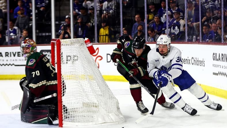 Feb 21, 2024; Tempe, Arizona, USA; Toronto Maple Leafs center Auston Matthews (34) moves the puck against the net against Arizona Coyotes defenseman Juuso Valimaki (4) during the first period at Mullett Arena. Mandatory Credit: Mark J. Rebilas-USA TODAY Sports
