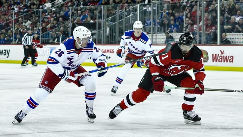 Feb 22, 2024; Newark, New Jersey, USA; New Jersey Devils defenseman Jonas Siegenthaler (71) and New York Rangers left wing Jimmy Vesey (26) pursue the puck during the first period at Prudential Center. Mandatory Credit: John Jones-USA TODAY Sports